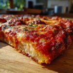 A close-up, low-angle shot showing the thick, textured interior of the chicken crust pizza with melted cheese and rich tomato sauce.