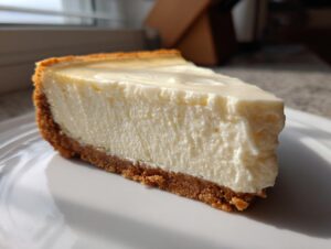 Close-up of a thick slice of creamy Keto cheesecake showing the graham cracker crust and rich filling.