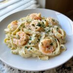 A close-up of creamy shrimp alfredo pasta topped with grated Parmesan and fresh parsley.