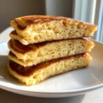 Close-up of three fluffy almond flour pancakes stacked, showing their light, airy interior texture.