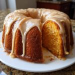 A moist sweet potato pound cake in a bundt shape, drizzled with a thick caramel glaze, with one slice cut out.