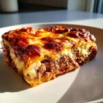Close-up of a hearty slice of Lasagna with Cottage Cheese showing rich meat filling and a bubbly, browned cheese topping.
