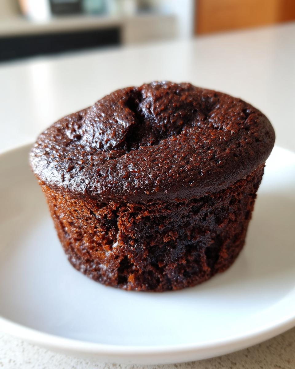 A single, rich, dark brown easy chocolate cupcakes sitting on a white plate.