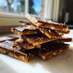 A stack of broken pieces of saltine cracker toffee showing the layers of cracker, caramel, and chocolate topping.
