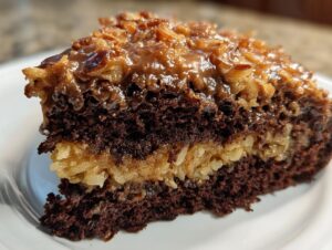 Close-up of a rich slice of german chocolate cake recipe showing dark chocolate layers and coconut-pecan filling.