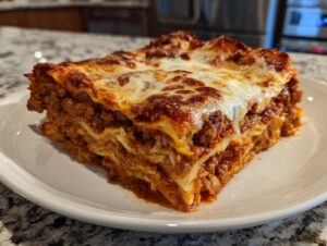 A thick, layered slice of homemade lasagna with rich meat sauce and browned, melted cheese topping served on a white plate.