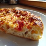 Close-up of a thick slice of pizza showing the airy crumb structure made from sourdough discard pizza dough.