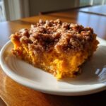 A close-up of a rich, orange slice of southern sweet potato casserole topped with brown sugar streusel.