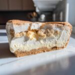 Cross-section view of a rich sugar cookie cheesecake slice showing a graham cracker crust, creamy filling, and cookie crumble topping.