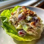 Close-up of creamy Waldorf salad featuring grapes, celery, and walnuts served in a crisp lettuce cup.