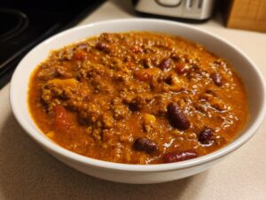 Close-up of a white bowl filled with rich, thick pumpkin chili featuring ground meat and kidney beans.