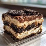 A decadent slice of layered dirt cake featuring cream, chocolate pudding, and crushed cookies, topped with a whole Oreo.