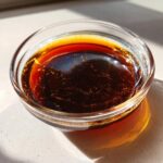 Close-up of rich, dark homemade teriyaki sauce glistening in a small clear glass bowl.