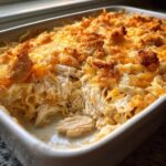 A close-up of a creamy chicken noodle casserole with shredded chicken, noodles, melted cheese, and a crunchy breadcrumb topping.
