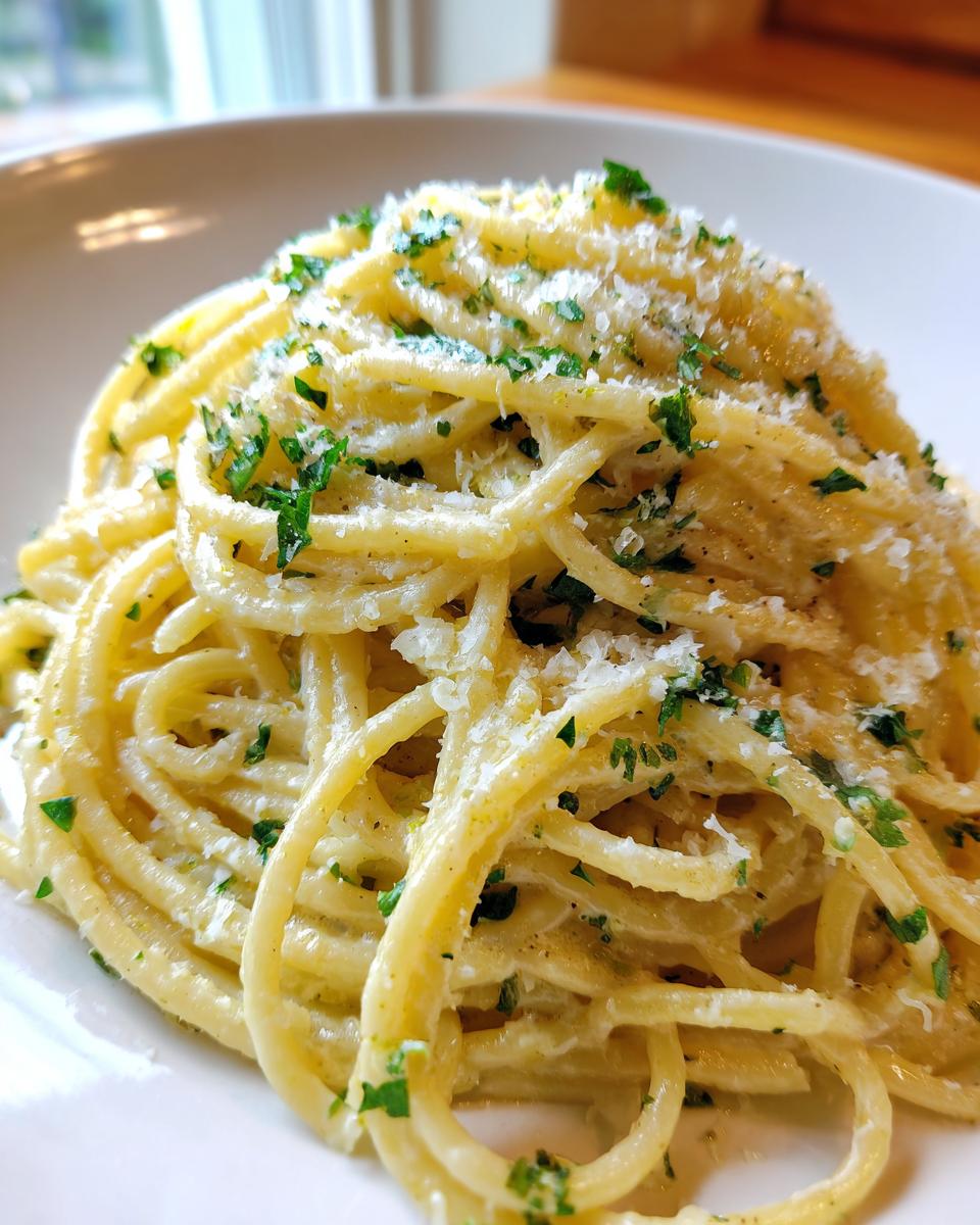 Close-up of a serving of Creamy Lemon Pasta coated in a light sauce, topped with grated Parmesan cheese and fresh chopped parsley.