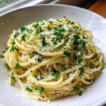 A close-up shot of a serving of Creamy Lemon Pasta tossed in a light sauce, topped with fresh parsley and grated cheese.