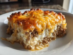 Close-up of a serving of french onion ground beef and rice casserole with a golden, bubbly cheese topping.