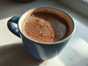Close-up of a steaming, frothy cup of Mexican hot chocolate in a rustic blue ceramic mug.