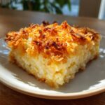 A square serving of creamy funeral potatoes recipe with a deeply browned, crispy topping.