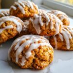 A close-up stack of soft, orange-hued persimmon cookies topped with thick white vanilla glaze.