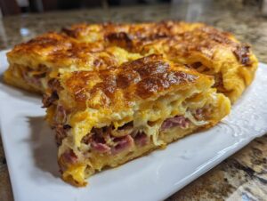 A close-up of a slice of homemade Reuben bake showing layers of corned beef, cheese, and crust.