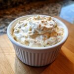 A close-up of creamy, chunky homemade tartar sauce served in a small white fluted ramekin.