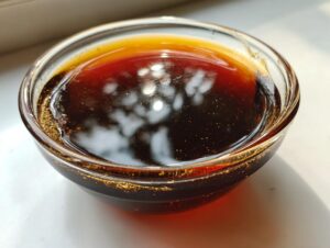 Close-up of rich, dark homemade teriyaki sauce glistening in a clear glass bowl.