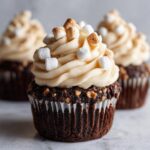 Close-up of a rich chocolate hot chocolate cupcake topped with creamy frosting and toasted mini marshmallows.