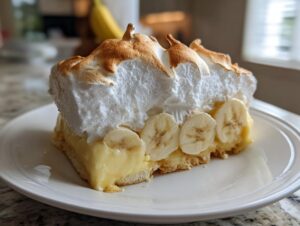 A generous slice of old-fashioned banana pudding featuring creamy filling, sliced bananas, and toasted meringue topping.