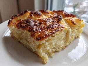 Close-up of a thick slice of creamy potatoes au gratin with a deeply browned, cheesy crust.