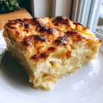 A rich, thick slice of potatoes au gratin with layers of creamy sauce and a deeply browned, cheesy top.