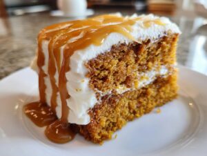 A moist slice of pumpkin poke cake layered with cream cheese frosting and drizzled heavily with caramel sauce.