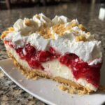 A generous slice of strawberry shortcake cheesecake featuring a graham cracker crust, creamy filling, strawberry topping, and whipped cream.