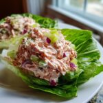 Close-up of creamy salmon salad served in crisp lettuce cups with celery and red onion.