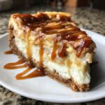 A decadent slice of apple pie cheesecake topped with warm apple slices and rich caramel sauce.