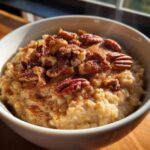 Close-up of hot apple cinnamon oatmeal topped generously with pecans and cinnamon.