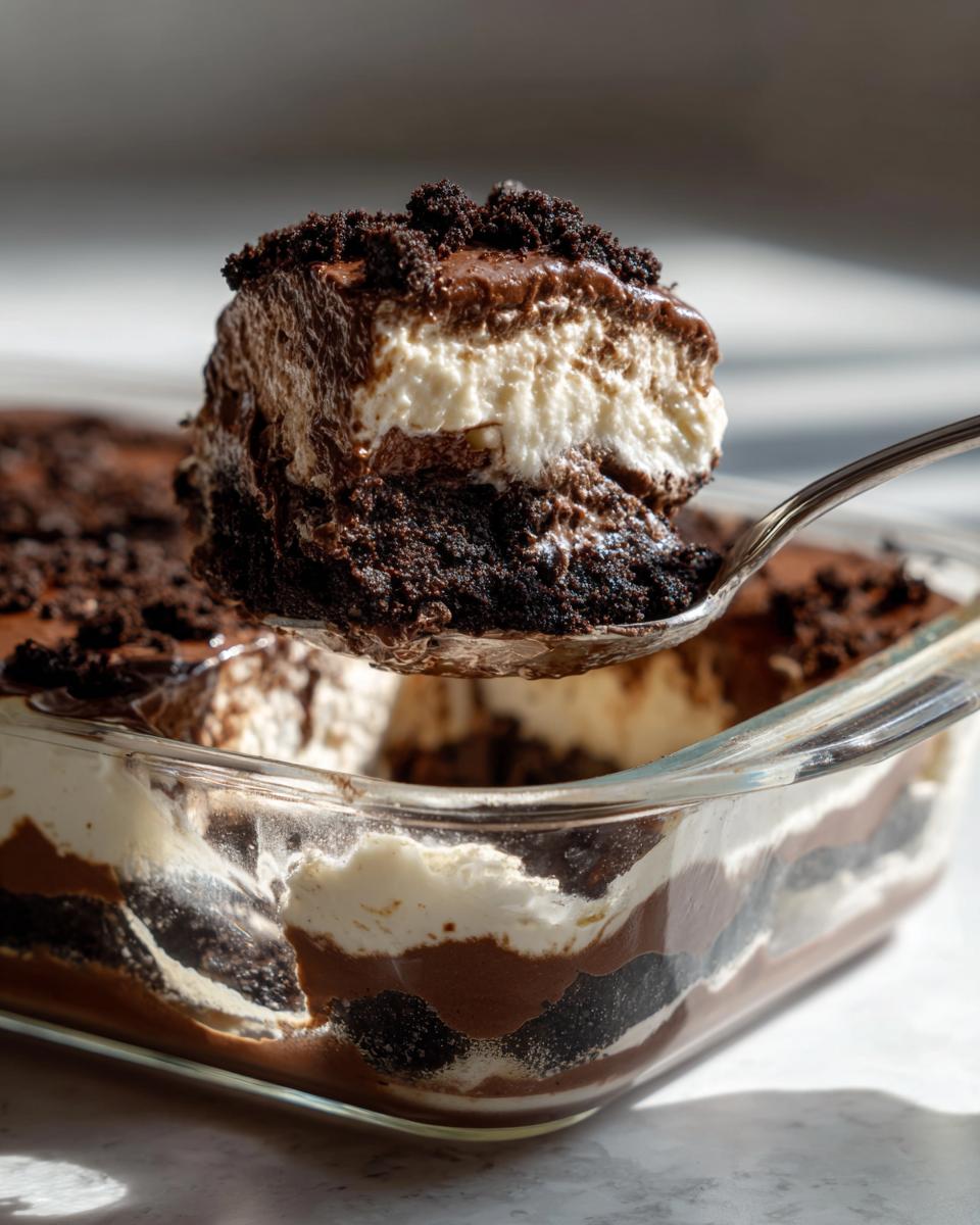 A spoonful of Baileys Chocolate Cheesecake Trifle showing layers of chocolate cake, cream, and topping.