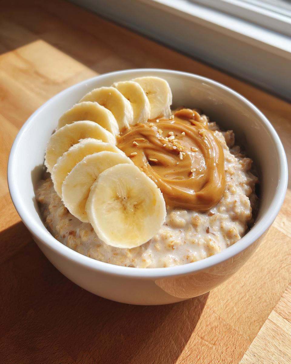 A close-up of creamy banana oatmeal topped with sliced bananas and a swirl of peanut butter.