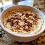 Close-up of a creamy onion dip topped generously with caramelized onions and drizzled with oil.