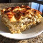 A generous slice of creamy chicken alfredo lasagna with layers of pasta, shredded chicken, and a browned, cheesy top.