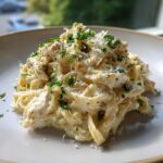 Close-up of creamy chicken fettuccine alfredo pasta topped with grated Parmesan and fresh parsley.