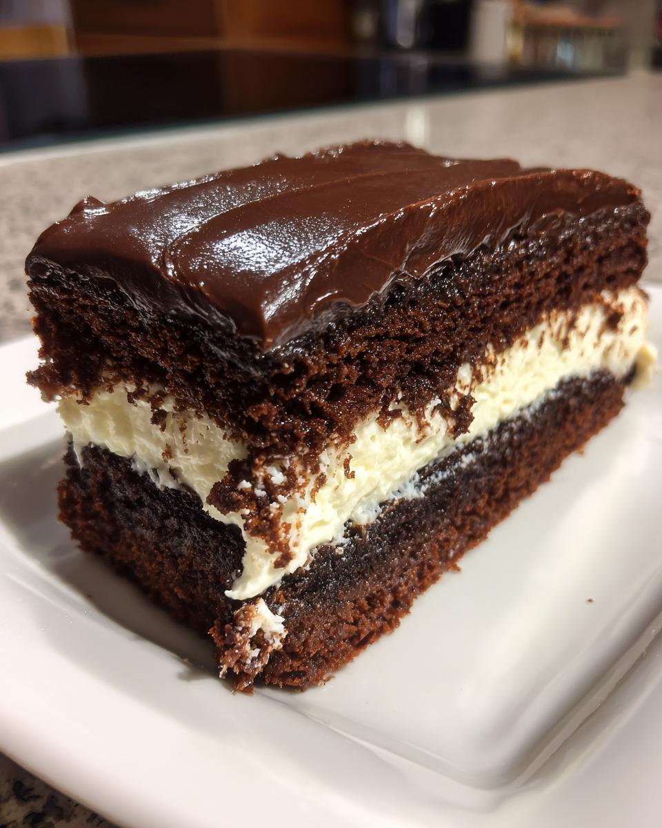 A rich slice of chocolate Italian love cake featuring dark cake layers and a thick white cream filling, topped with chocolate ganache.