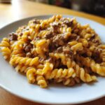 A close-up serving of creamy beef pasta featuring fusilli noodles coated in a rich, cheesy sauce with ground beef.