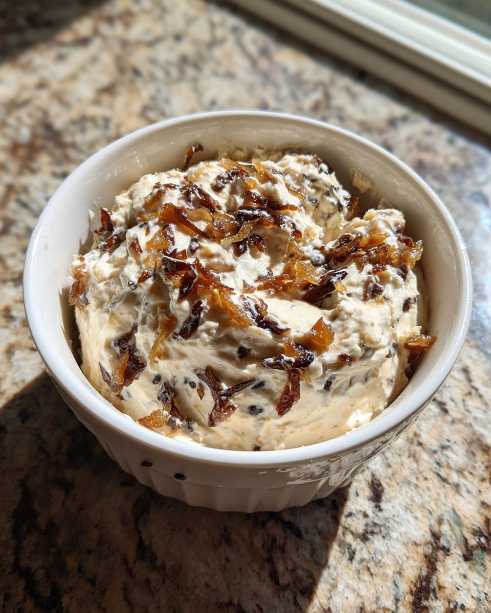 A white bowl filled with creamy onion dip, topped generously with crispy fried onions.