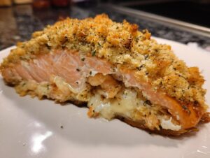 A cross-section view of delicious stuffed salmon with a golden, crispy topping and creamy shrimp filling.