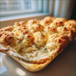 Close-up of a freshly baked chicken cobbler casserole with golden biscuit topping bubbling over creamy filling.