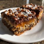 Close-up of two slices of magic cookie bars showing gooey caramel, chocolate, pecans, and coconut topping.