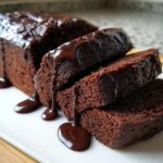 Close-up of rich, dark slices of hot fudge brownie bread generously covered in dripping chocolate fudge sauce.