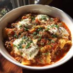 A close-up bowl of rich Instant Pot Lasagna Soup topped with dollops of ricotta cheese and fresh parsley.