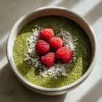 Overhead view of bright green matcha chia pudding topped with fresh raspberries and shredded coconut.